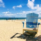 A general landscape view of Fort Lauderdale Beach Sidewalk at Midday in a summer season, with a big summer beach chair for tourist to take pictures, some of them, enjoying the weekend during the Corona Virus Pandemic illness breakdown.